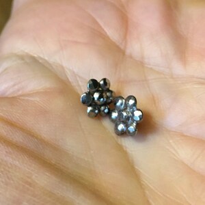 May include: Two silver flower-shaped earrings with a textured surface.