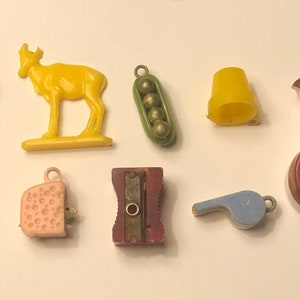 以下が含まれることがあります： シカ、ホイッスル、鉛筆削り、エンドウ豆のさや、ベルなど、10個のビンテージプラスチックおもちゃのコレクションです。