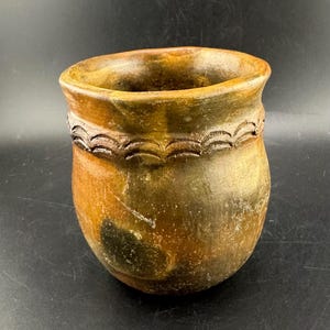 Op de afbeelding: Een bruine en groene keramische pot met een golvend ontwerp rond de bovenkant.