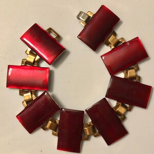 Peut inclure: Un bracelet rouge et or avec des maillons rectangulaires en &eacute;mail rouge. Le bracelet a une fermeture &agrave; fermoir.