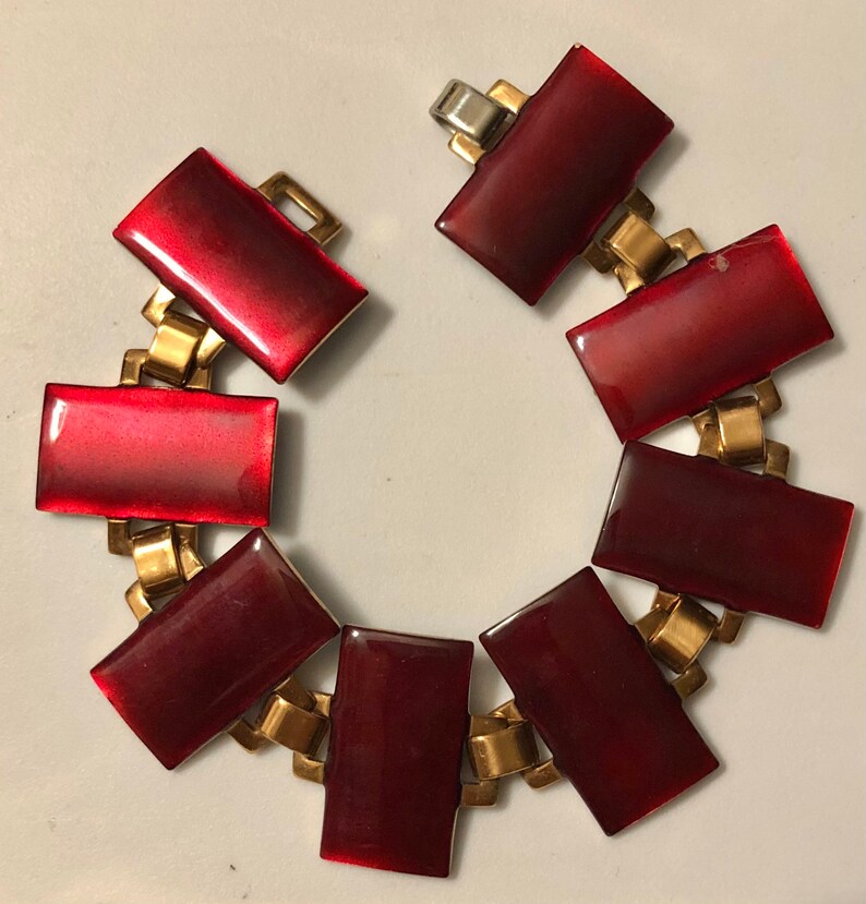 Peut inclure: Un bracelet rouge et or avec des maillons rectangulaires en &eacute;mail rouge. Le bracelet a une fermeture &agrave; fermoir.