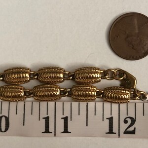 May include: Gold tone chain necklace with a textured oval link design. The necklace is 11 inches long and has a lobster clasp closure. The chain is marked "ROBERT".