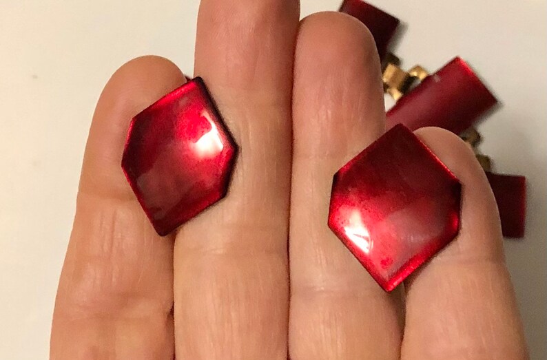 Peut inclure: Deux boutons hexagonaux de couleur rouge avec une finition brillante.