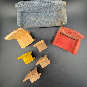 May include: A miniature blue fabric sofa with a rectangular shape and several wooden toy pieces in various colors. The wooden pieces include a natural wood color, yellow, and red.