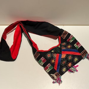 May include: A black and red embroidered shoulder bag with colorful geometric patterns and fringe details.