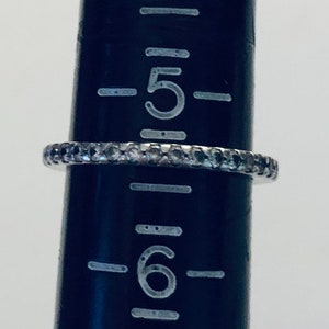 May include: A silver band ring with a row of small, clear stones. The ring is sized 5.5.