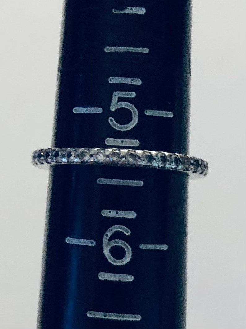 May include: A silver band ring with a row of small, clear stones. The ring is sized 5.5.