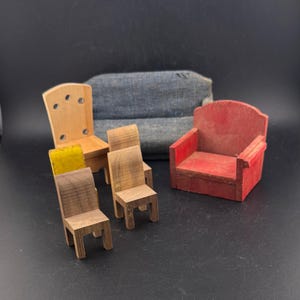 May include: A collection of miniature wooden furniture, including chairs and a small red armchair. The chairs vary in design and wood tone, with one featuring a yellow seat cushion. A small, blue fabric sofa is in the background.