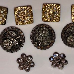 May include: Assortment of vintage buttons in gold and silver tones. Some buttons feature a floral design, while others have a geometric pattern.