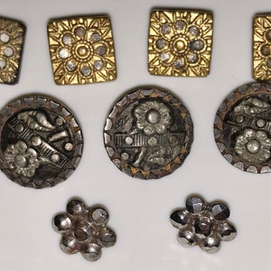 May include: Assortment of vintage buttons in silver and gold tones. Some buttons feature a floral design, while others have a geometric pattern.
