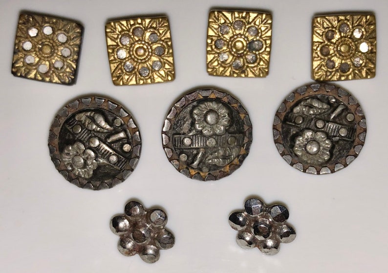 May include: Assortment of vintage buttons in silver and gold tones. Some buttons feature a floral design, while others have a geometric pattern.