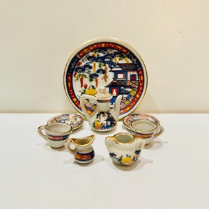 Könnte beinhalten: Ein Miniatur-Tee-Set mit einem blauen und weißen Blumenmuster. Das Set enthält eine Teekanne, eine Kanne, eine Zuckerdose, zwei Tassen und zwei Untertassen.