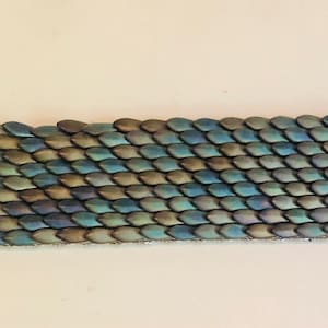 Könnte beinhalten: Ein silbernes Armband mit einem schimmernden Schuppenmuster in Blau, Grün und Braun.