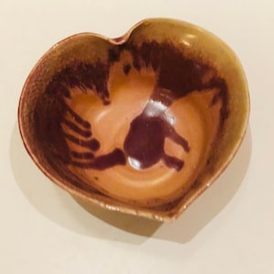 Könnte beinhalten: Eine herzförmige Keramikschale mit brauner und violetter Glasur. Die Schale hat ein einzigartiges, handgemaltes Design.