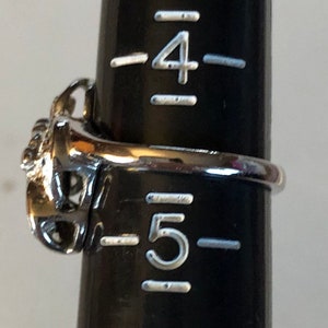 May include: A silver ring with a decorative design, sized for a size 5 finger.