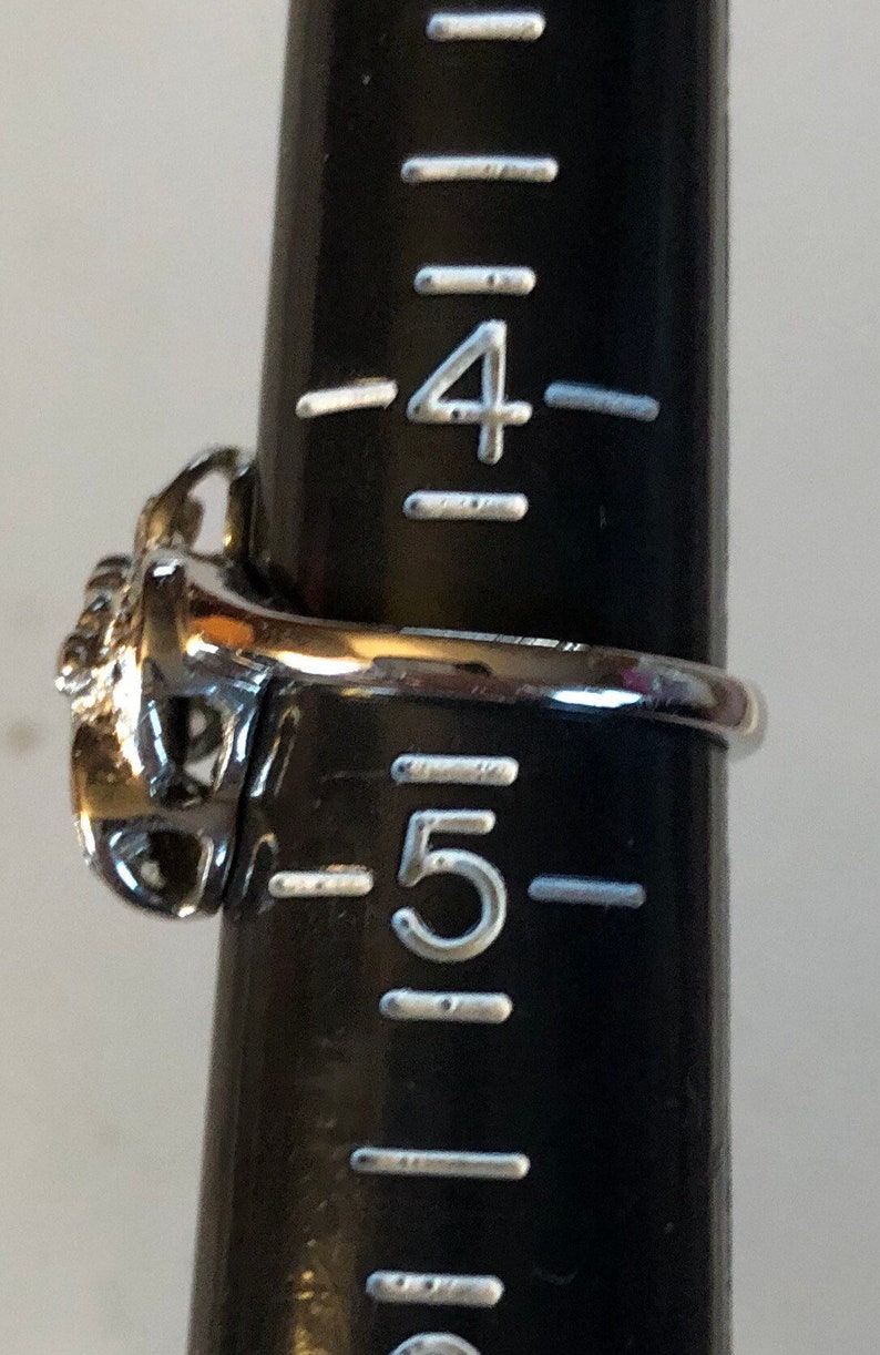 May include: A silver ring with a decorative design, sized for a size 5 finger.
