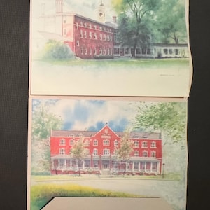 May include: Two watercolor paintings of buildings with red brick exteriors and white trim. The top painting shows a building with a clock tower and green trees. The bottom painting shows a building with a porch and a sign that reads "The Hotel".
