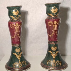 Puede incluir: Un par de candelabros ornamentados con un diseño verde, rojo y dorado. Los candelabros están hechos de cerámica y tienen un estilo tradicional.