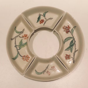 May include: A white ceramic serving dish with four sections. Each section features a floral design with green leaves and red berries. The dish is ideal for serving snacks, dips, or appetisers.