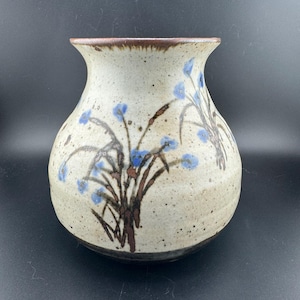 Può includere: Un vaso in ceramica bianca con un bordo marrone e un motivo floreale marrone e blu.