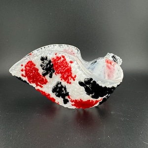 May include: A clear glass bowl with a textured surface. The bowl is decorated with red, black, and white dots.