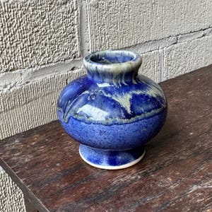 May include: A small, round blue and white ceramic vase with a mottled glaze.