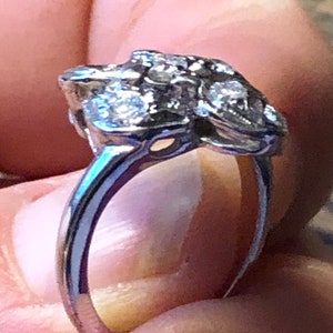 May include: A silver ring with a cluster of small diamonds set in a floral design.