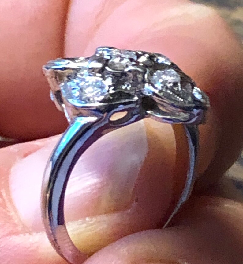 May include: A silver ring with a cluster of small diamonds set in a floral design.