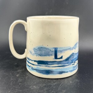Peut inclure: Mug artisanal en c&eacute;ramique avec un gla&ccedil;age mouchet&eacute; de couleur cr&egrave;me. Le mug a un corps large et arrondi et une anse robuste. L'int&eacute;rieur est d'une teinte plus fonc&eacute;e et terreuse. Pour boissons chaudes ou froides.
