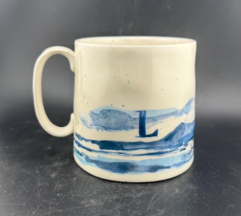 Peut inclure: Mug artisanal en c&eacute;ramique avec un gla&ccedil;age mouchet&eacute; de couleur cr&egrave;me. Le mug a un corps large et arrondi et une anse robuste. L'int&eacute;rieur est d'une teinte plus fonc&eacute;e et terreuse. Pour boissons chaudes ou froides.