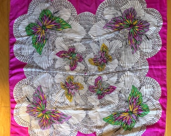 May include: A pink square scarf with a white background and a pattern of colorful butterflies. The butterflies are outlined in black and have pink, green, yellow, and purple accents.