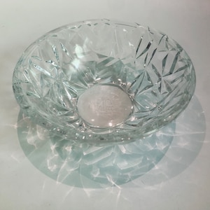 Pode incluir: Uma tigela de vidro transparente com um padrão de diamante. A tigela está vazia e tem uma superfície reflexiva.