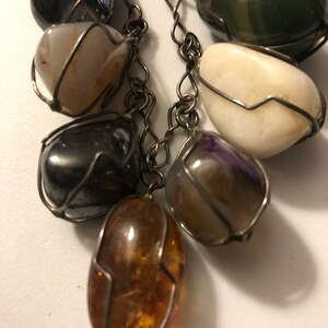 Pode incluir: Um bracelete de corrente de prata com uma variedade de contas de pedras preciosas, incluindo ametista, &aacute;gata, &acirc;mbar e hematita. Cada conta &eacute; envolvida em fio de prata.