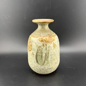 以下が含まれることがあります： 丸みを帯びた胴体と細い首を持つ小さな陶器の花瓶。花瓶は、茶色、緑、白の斑点模様の釉薬で装飾されています。