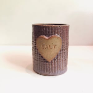 Peut inclure: Un pot à sel en céramique violet avec un motif en forme de cœur qui dit "SALT" dessus.
