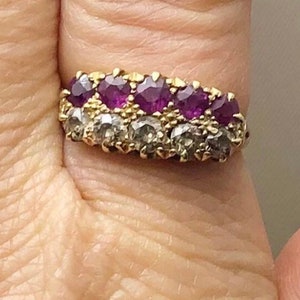 May include: A gold band ring with a row of purple gemstones surrounded by smaller clear gemstones.