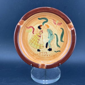 Posacenere vintage in ceramica Pennsbury Pottery, raffigurante una coppia Amish che si bacia (Such Schmootzers Kissing Amish Couple), arte popolare della Pennsylvania olandese. Venduto così com'è (piccola scheggiatura sul bordo).