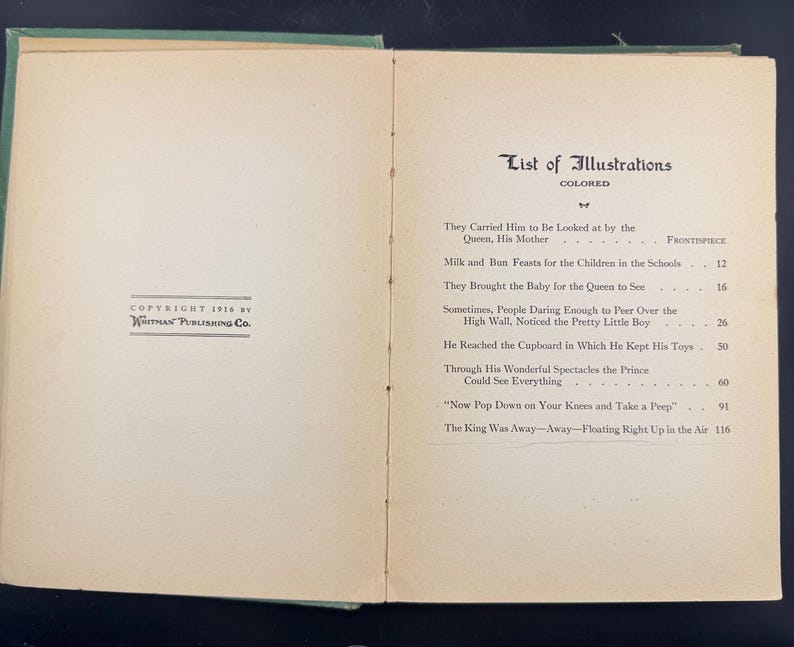 May include: Open book with a green cover, showing a list of illustrations. The text includes titles such as "They Carried Him to Be Looked at by the Queen, His Mother" and "Milk and Bun Feasts for the Children in the Schools." Copyright 1916 by Whitman Publishing Co.
