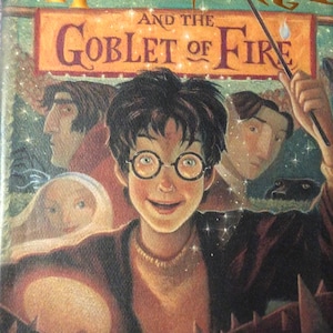 Puede incluir: Portada del libro "Harry Potter y el cáliz de fuego". El título dorado está sobre una ilustración de Harry Potter con gafas y otros personajes al fondo. El nombre del autor, J.K. Rowling, está en la parte inferior.
