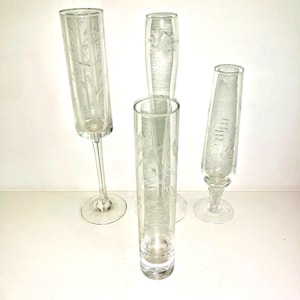 May include: Four clear glass vases with etched designs. The vases are of different heights and shapes.