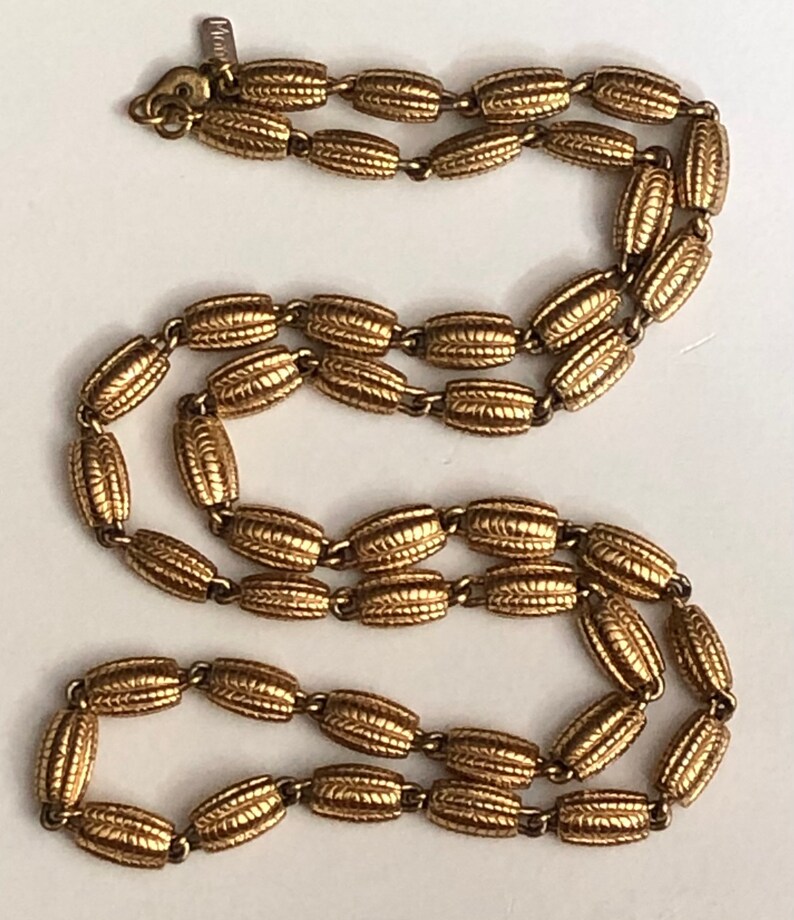 May include: A gold-toned chain necklace with a textured, oval-shaped link design. The necklace is made of metal and has a simple, elegant style.