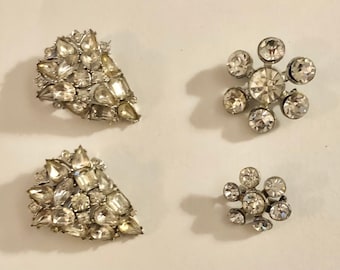 Può includere: Quattro spille di strass, due a forma di lacrima e due a forma di fiore.