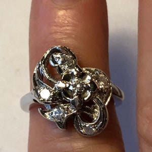 May include: A silver ring with a floral design and multiple small diamonds.