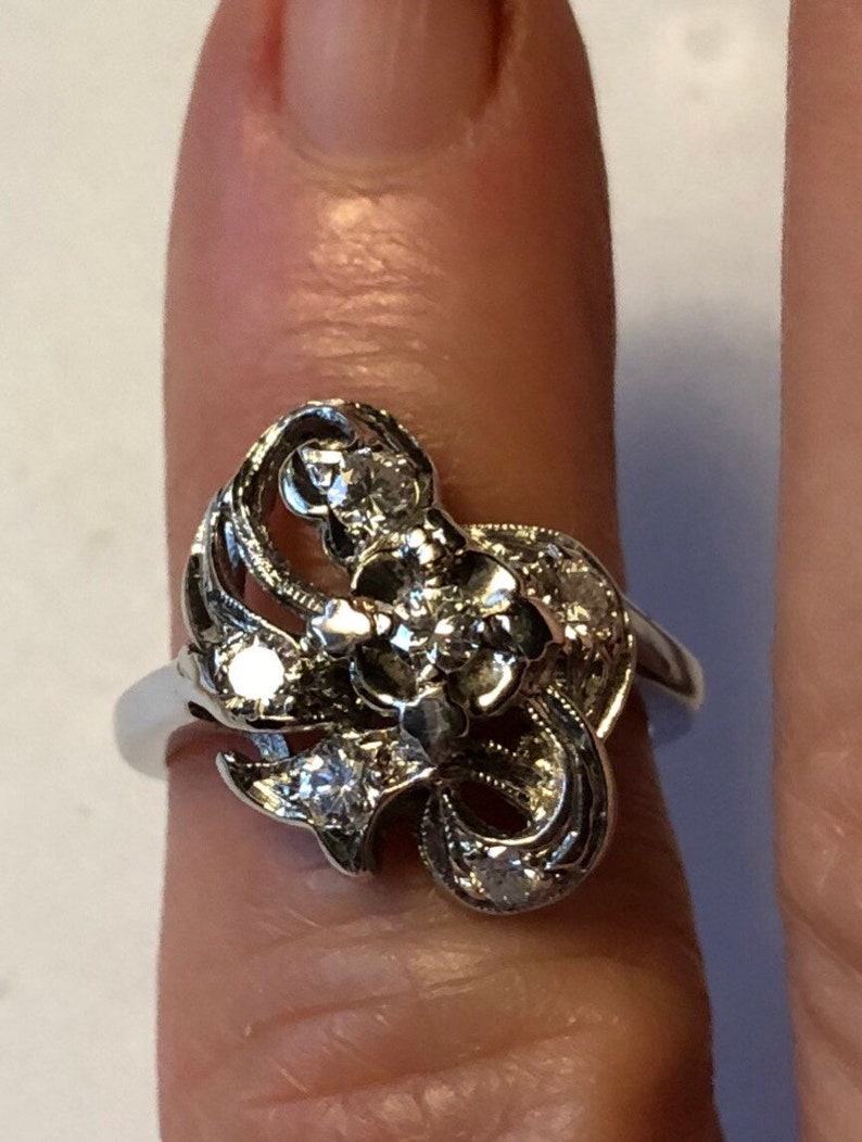May include: A silver ring with a floral design and multiple small diamonds.