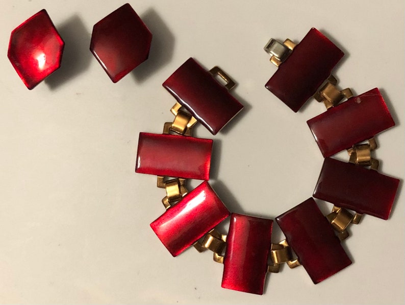 Peut inclure: Un bracelet en &eacute;mail rouge avec une cha&icirc;ne dor&eacute;e et une paire de boucles d'oreilles assorties. Le bracelet a des maillons de forme rectangulaire et les boucles d'oreilles sont hexagonales.