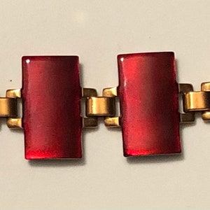 Peut inclure: Un bracelet en verre rouge avec des maillons en m&eacute;tal dor&eacute;. Le bracelet est compos&eacute; de pi&egrave;ces rectangulaires en verre rouge reli&eacute;es par des maillons en m&eacute;tal dor&eacute;.