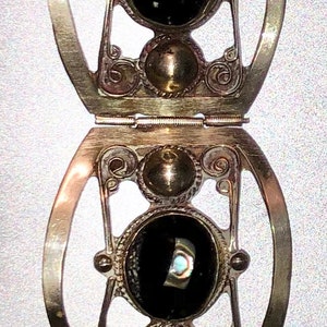 Puede incluir: Pulsera plateada con cuatro eslabones ovalados con dise&ntilde;os de filigrana ornamentados. Cada eslab&oacute;n tiene una piedra negra central con acentos iridiscentes. Cierre de broche, probablemente vintage.