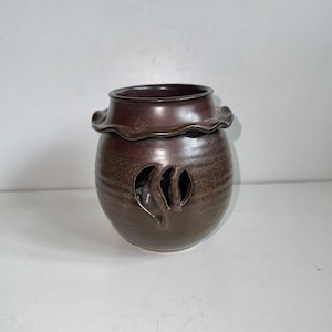 May include: A brown ceramic oil burner with a scalloped rim and a cut-out design of a leaf.