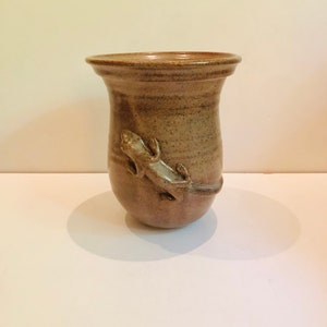 Puede incluir: Un jarrón de cerámica marrón con una superficie texturizada y un diseño de lagarto en el lateral.
