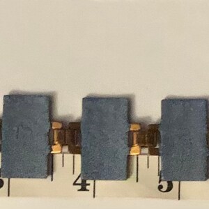 Peut inclure: Un bracelet en cha&icirc;ne dor&eacute;e avec des maillons rectangulaires bleus, mesur&eacute; sur une r&egrave;gle en pouces. Le bracelet mesure 7 pouces de long.